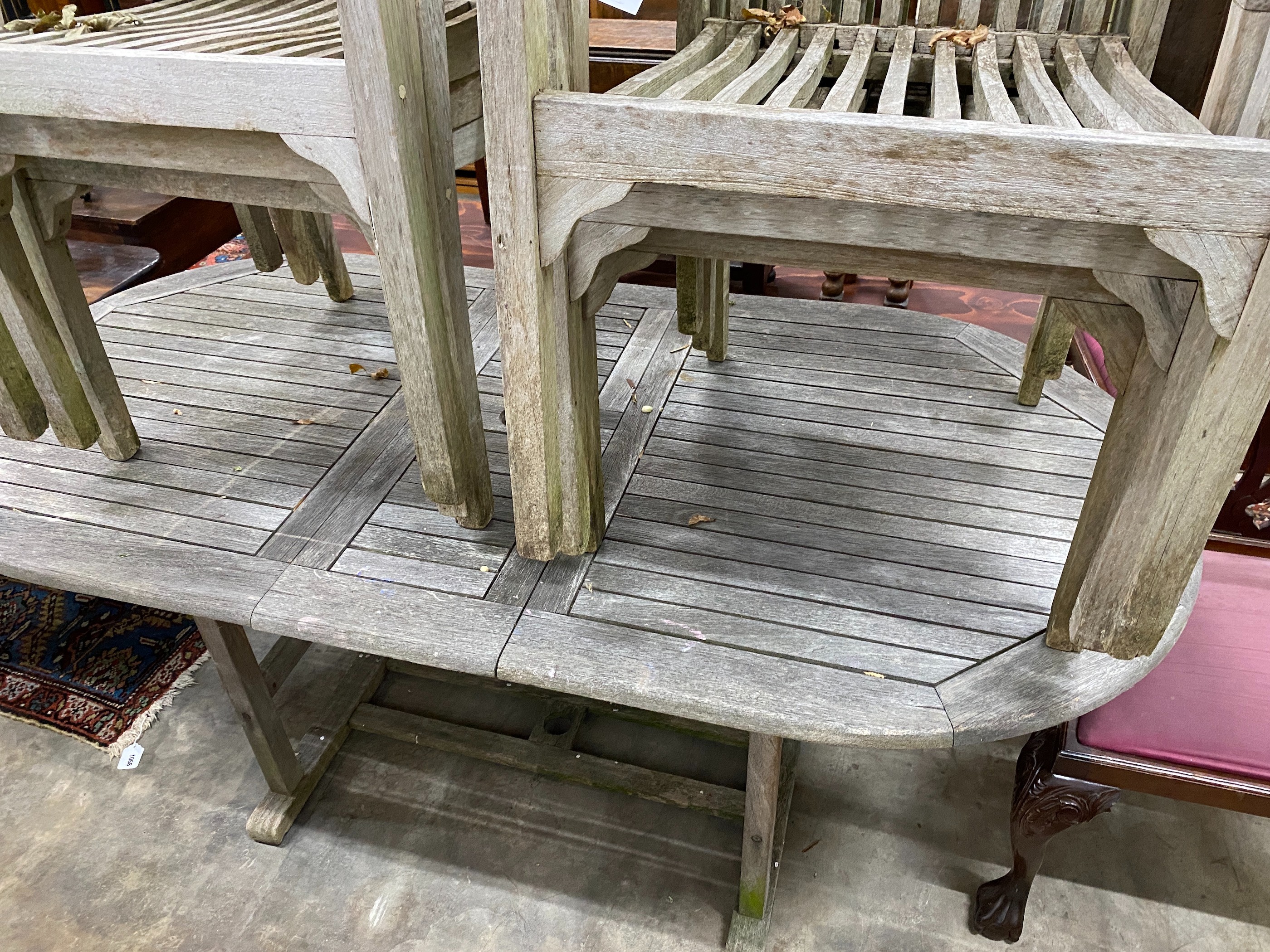 A weathered teak extending garden table, 180cm extended, width 90cm, height 74cm and six stacking chairs